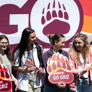 students holding up grizzly bear paw print signs that say "I decided to Go Griz"