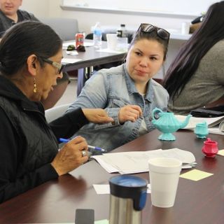 tow women sit at a table in discussion