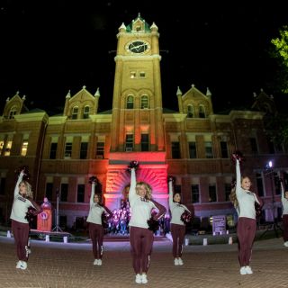 Members of the UM Dance Team perform in front of Main Hall at night during the Homecoming Pep Rally.