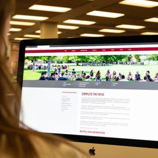 Laptop screen displays UM web with directions on completing a FAFSA