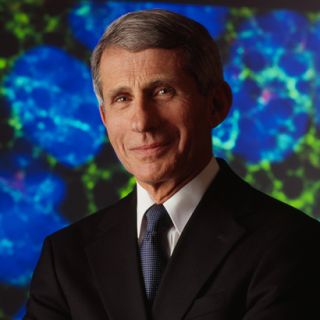 Dr. Anthony Fauci stands facing the camera with his arms crosssed
