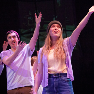 The 2020 Cast of "Spring Awakening" raising their arms in song. 