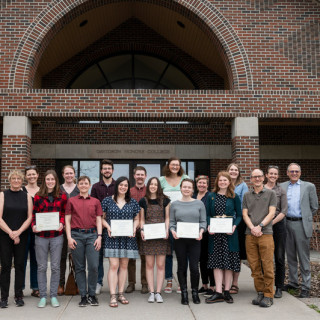 A group of students and faculty stand in front of the DHC