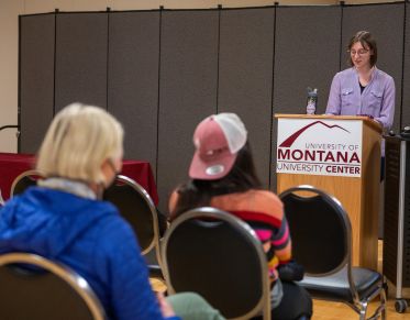 A speaker presenting to audience at a campus event.