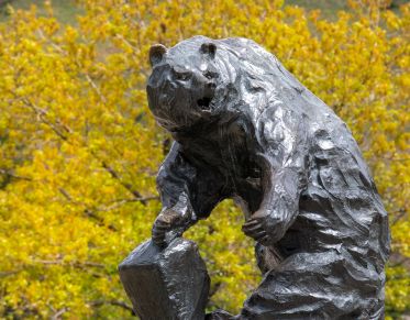 Griz statue with trees and flowers