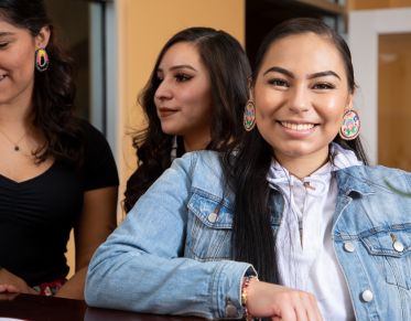 Three native students standing at a counter