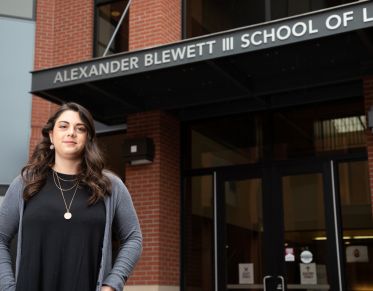 Female student stands under the School of Law entrance