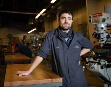 Student stands in classroom with equipment