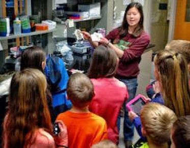 A role model shows a group of students through a research lab.