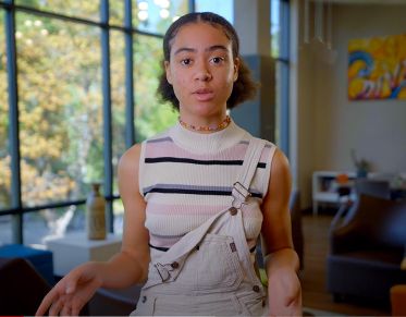 UM student Abbe Watson looks at the camera and speaks while standing in the Branch Center of the University Center at UM.