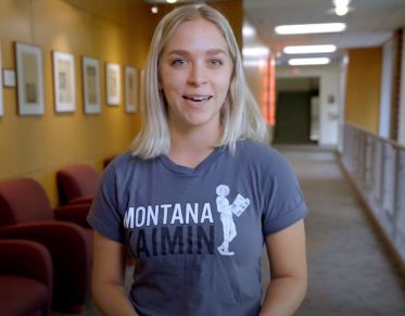 UM student Addie Slanger speaks to the camera while walking through the hallway outside the student newspaper office at UM.