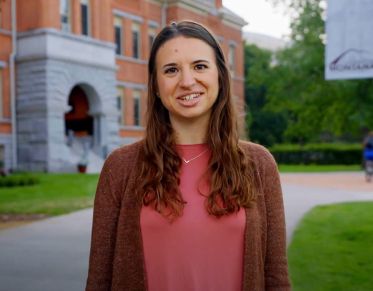 UM student Amy Violante speaks at the camera while walking around the Oval in front of Main Hall.