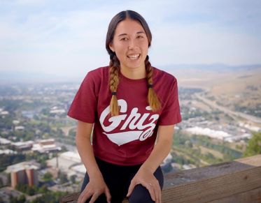 UM student Kennedy Marx talks to the camera while sitting above the Missoula Valley after hiking up Mount Sentinel.