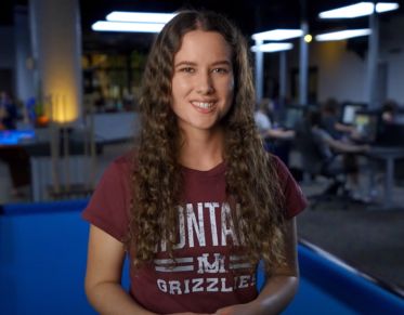 UM student Tessa Johnson looks at the camera and speaks while leaning against a pool table in the Game Room at UM's University Center.