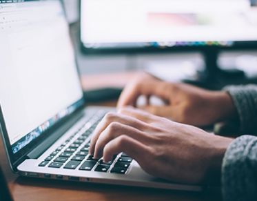 Hands typing on a laptop keyboard