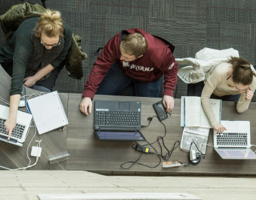 Three students each using laptops and collaborating