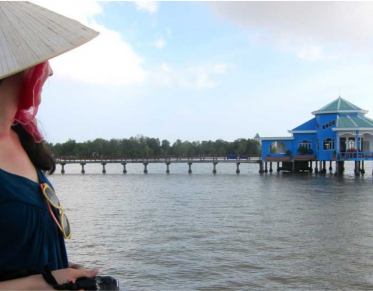 young woman wearing a hat standing at the edge of a body of water
