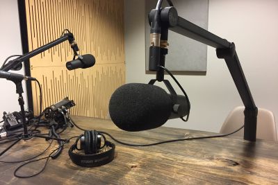 An image of two microphones with headphones and equipment on a desk 