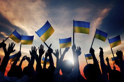 A picture of people holding Ukrainian flags at sunset