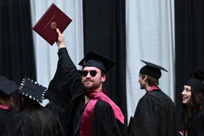 A student holds aloft his diploma at a recent UM graduation ceremony.