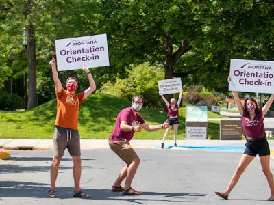 Three Advocates hold Orientation Check In signs