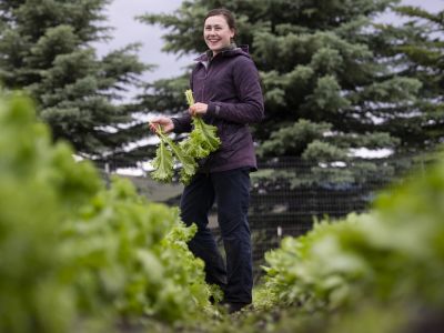 UM student Lyris Daker laughs and looks on as she harvests mustard at the PEAS Farm