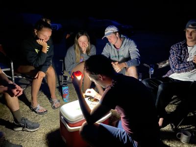Grad students in the field at night gathered around a flashlight.