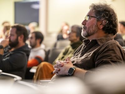bearded man watching a research seminar