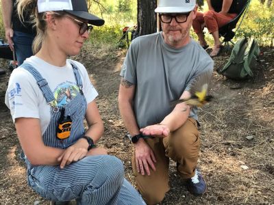 An UMBEL biologist helps a visitor release a Black-headed Grosbeak.