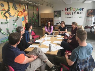 A group of people meet around a large table in EMPower Place.