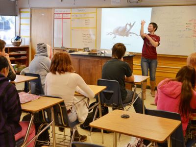 Wildlife biology role model presents on beetles in a high school classroom.