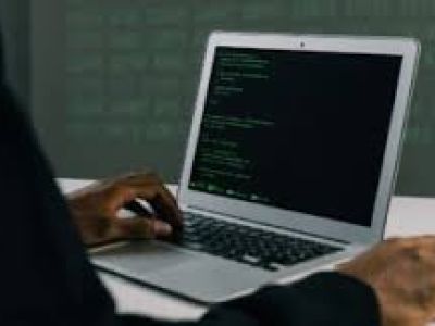 hands typing on a laptop with green characters on the screen