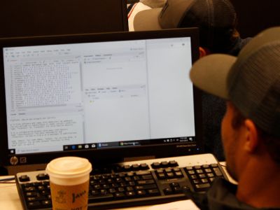 view of a students laptop screen and others in a full classroom