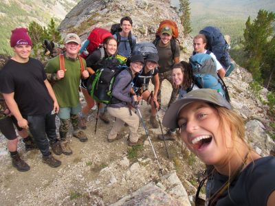 Students on the Freshman Wilderness Experience pose for a group photo while on a hike at the top of a mountain.