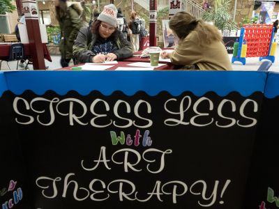 Two students color at a table during Stress Less