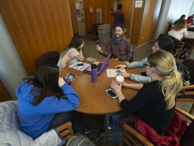 Students sit around a table working on homework