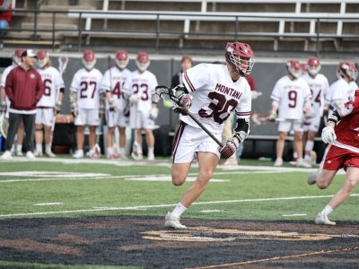 A Griz Lacrosse player running with the ball during a home game against Washington State