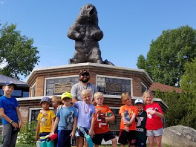 Children and guardian posing in front of a bear statue