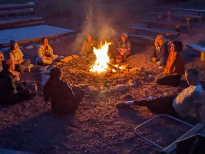 people sit around a bonfire at night