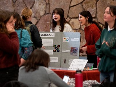 students smile in front of display table