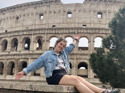 Female sitting in front of a Colosseum 