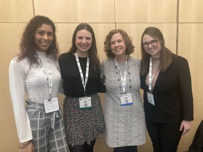 Three graduate students and Dr. Anisa Goforth standing side by side at a conference