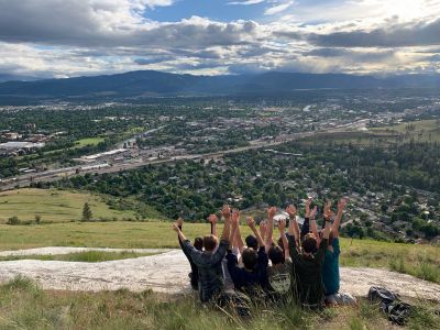 Schwanke participants sitting on top of Mount Sentinel with their arms up in the air 