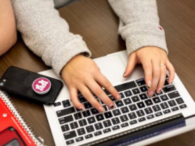 A student's hands using the keyboard on a laptop