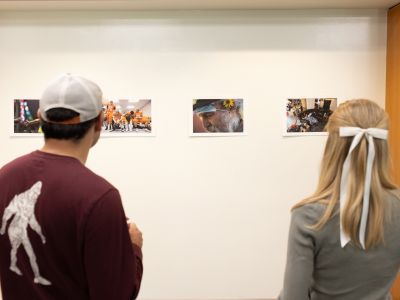 People hang photography in a gallery.