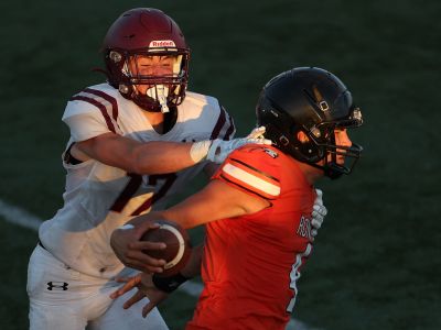 Football players in helmets spar on the field. 