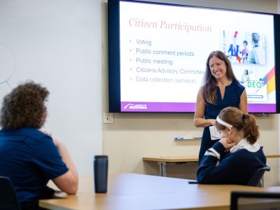 A teacher presenting  Citizen Participation with a powerpoint