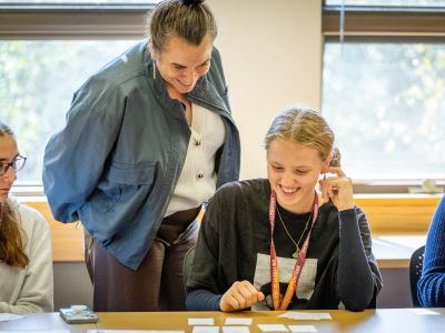 A teacher standing over a student looking at flash cards