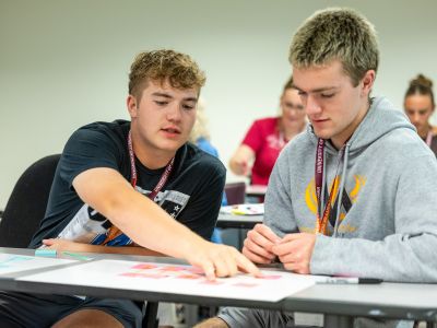 A student showing another student something on paper.