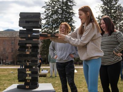 Students outside playing Jenga with an oversized Jenga set